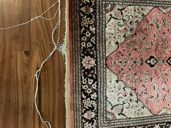 Tapis clair sur parquet, frange à reprendre.